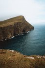 Océano y acantilado rocoso verde en las Islas Feroe - foto de stock