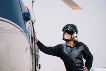 Pilot girl poses with her helicopter and helmet — Stock Photo