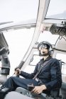 Serious female pilot in helmet and sunglasses sitting in helicopter — Stock Photo