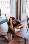 Junge nachdenkliche Frau sitzt am kleinen Holztisch im Zimmer und schreibt Tagebuch — Stockfoto