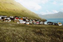 Vista al pequeño pueblo con casas coloridas y montañas verdes en las Islas Feroe - foto de stock