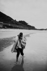 Persona caminando en la costa húmeda y tomando fotos - foto de stock