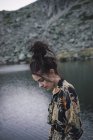 Giovane donna in abito elegante fantasia in piedi vicino lago increspatura — Foto stock