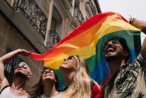 Grupo de amigos con bandera de orgullo gay en la ciudad de Madrid - foto de stock