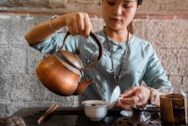 Junge Asiatin gießt Wasser aus Kanne und kocht Tee bei traditioneller Zeremonie — Stockfoto