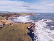 Incredibile vista drone di bel mare ondeggiante vicino alla riva con campi agricoli e insediamento nella giornata di sole in Asturie, Spagna — Foto stock