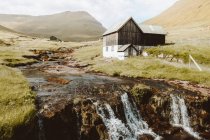 Waterfall and wooden rural house on hillside on Feroe Islands — Stock Photo