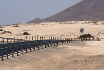 Carretera con señal y montañas en el desierto de Fuerteventura, Islas Canarias - foto de stock