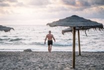 Forte vecchio che cammina sulla spiaggia — Foto stock