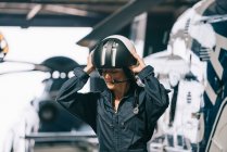 Pilote fille pose avec son hélicoptère et casque — Photo de stock