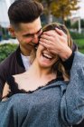 Fröhlicher junger Mann bedeckt Augen lachender Freundinnen, während er fröhlich zusammen posiert. — Stockfoto