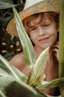 Garçon tenant du maïs dans le champ de maïs — Photo de stock