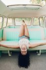 Весела молода брюнетка лежить на задньому сидінні ретро фургона під час подорожі в природі — стокове фото