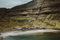Small picturesque village on coast at green cliff on Feroe Islands — Stock Photo