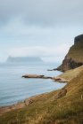Ocean and rocky cliff in overcast on Feroe Islands — Stock Photo