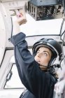 Зосереджена жінка-пілот в шоломі сидить і працює на вертольоті — стокове фото