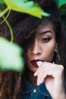 Sinnliche afrikanisch-amerikanische Frau steht vor grünem Busch und blickt in die Kamera — Stockfoto