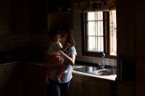 Woman in kitchen playing with baby — Stock Photo