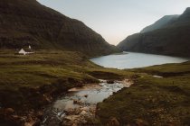 Solitario casetta in verdi montagne al lago in nuvoloso, Isole Feroe — Foto stock