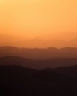 Hermosa vista del increíble terreno montañoso a la luz naranja del sol poniente - foto de stock