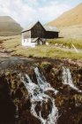 Водоспад і дерев'яні сільський будинок на схилі на Feroe острови — стокове фото
