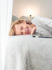 Милый смеющийся мальчик лежит на диване с цифровым планшетом — стоковое фото