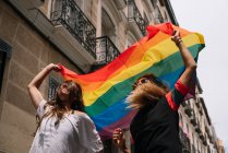 Casal lésbicas mulher com gay orgulho bandeira no o rua de madri cidade — Fotografia de Stock