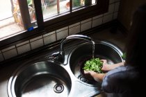 Donna che lava l'insalata in lavandino — Foto stock