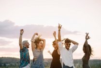 Group of young people in casual outfits laughing and dancing while having fun in beautiful countryside together — Stock Photo