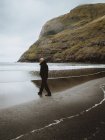 Man in warm clothes standing on shore of calm ocean on Feroe Island — Stock Photo