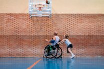 Спортсмени з обмеженими можливостями і маленька дівчинка в дії, граючи в критий баскетбол — стокове фото