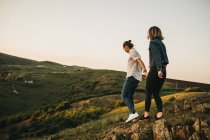 Вид сбоку юноши и девушки, идущих по каменистому холму, проводя время на природе вместе — стоковое фото