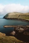Océano y acantilado rocoso verde en las Islas Feroe - foto de stock