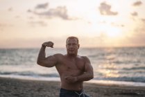 Сильний старий робить вправи на пляжі — стокове фото