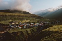 Blick auf ein kleines Dorf in großen grünen Bergen auf den Feroe Islands — Stockfoto