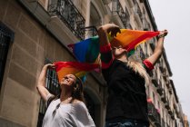 Pareja lesbiana con bandera de orgullo gay en la calle de Madrid - foto de stock
