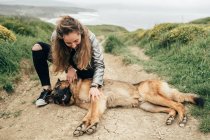 Jeune femme caressant chien dans la nature — Photo de stock