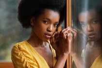 Side view of pretty African American female leaning on clean window glass — Stock Photo