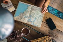 Руки жінки з картою на дерев'яному столі, планування подорожі — стокове фото