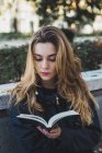 Молодая женщина читает книгу в городском парке — стоковое фото