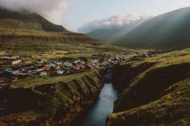 Vue d'un petit village dans de grandes montagnes verdoyantes sur les îles Feroe — Photo de stock