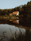 Grande maison avec toit orange construite en forêt et étang sur l'île de Feroe — Photo de stock