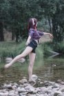 Rousse fille aux cheveux effectue des exercices au bord de la rivière — Photo de stock