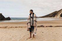 Человек в одеяле смотрит на берег — стоковое фото