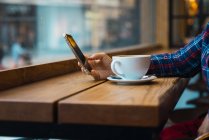 Mujer sentada en la cafetería con una taza de café - foto de stock