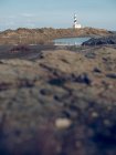Vista a la costa rocosa y la torre del faro en la orilla del mar. - foto de stock