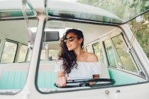 Mujer joven con confianza en gafas de sol conducir coche retro - foto de stock