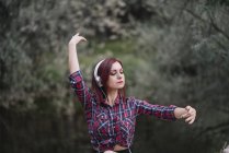 Rosso dai capelli ragazza ascolta la musica dal fiume — Foto stock