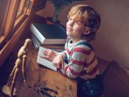 Мальчик сидит с книгой за столом — стоковое фото