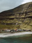 Pequeño pueblo pintoresco en la costa en el acantilado verde en las Islas Feroe - foto de stock